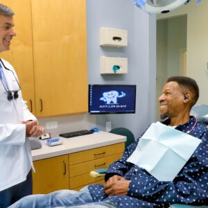 A doctor smiling at a young patient in a dental office.